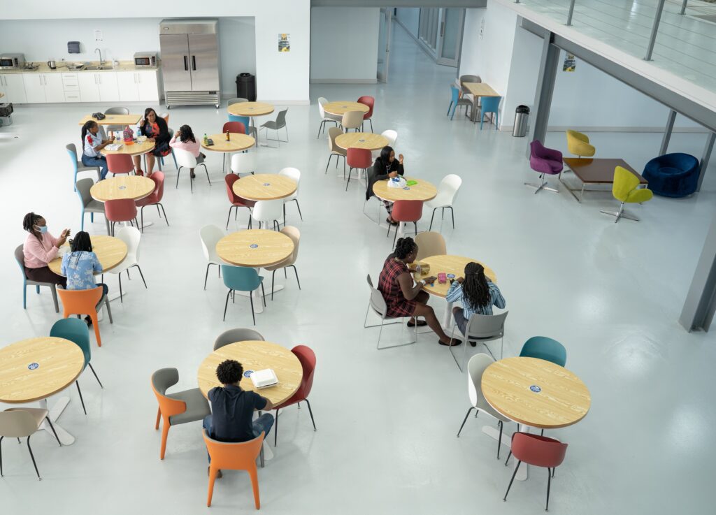 Image of the inside of itel's Saint Lucia site and contact center. The cafeteria and adjoining chill space features natural wood accents and pops of blue and green in the furnishings. 