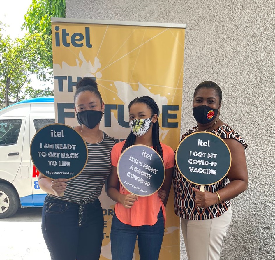 Image of three itel employees showing off some of the branded signs from the company's COVID-19 awareness campaign.