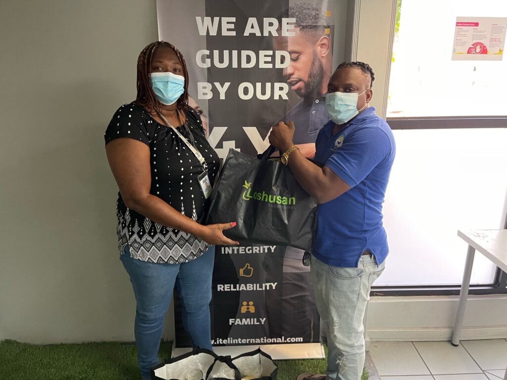 Image of an itel agent handing over bags of donations to a Yutes4Change Foundation representative in Kingston, Jamaica.