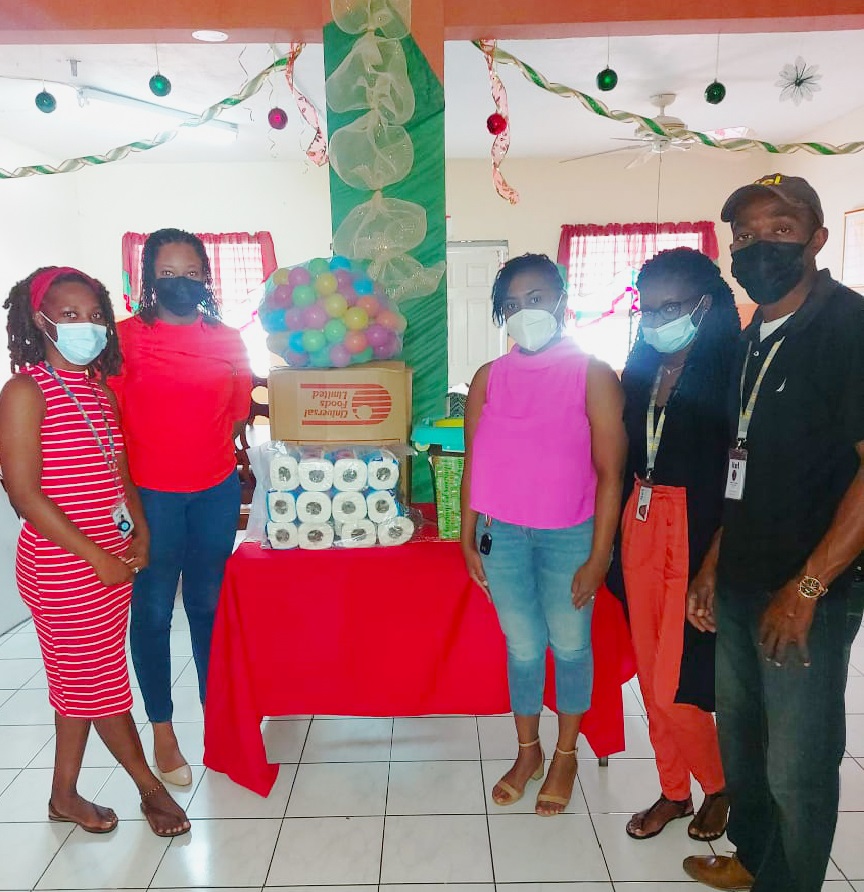 Image of itel employees handing over baskets filled with baby formula, diapers, toiletries, and books, donated by itel, and given to Blossom Gardens, a childcare facility in Montego Bay, Jamaica.