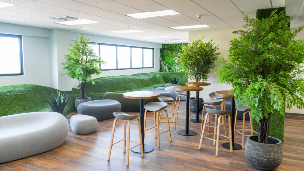 Image of one of itel's "Chill Spaces", in their newest, landmark customer experience center in Kingston, Jamaica. Rolling hills of faux grass, potted trees, botanical walls, and chairs made to look like natural stone formations make these unique employee break rooms a standout feature of the company's employee-centric environment.